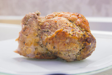 A piece of fried meat on a white plate close-up on a gray kitchen table