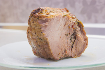 A piece of fried meat on a white plate close-up on a gray kitchen table