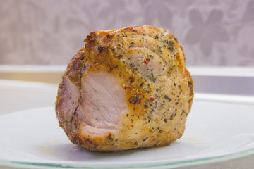 A piece of fried meat on a white plate close-up on a gray kitchen table