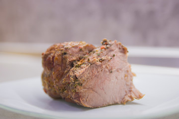 A piece of fried meat on a white plate close-up on a gray kitchen table
