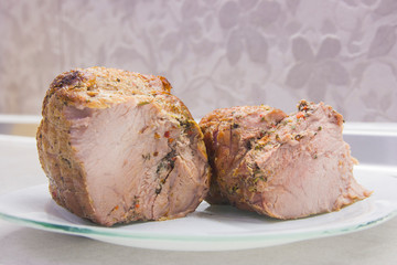 A piece of fried meat on a white plate close-up on a gray kitchen table