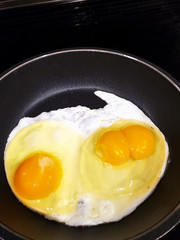 sunny side up double yolk eggs cooking in black frying pan on stove
