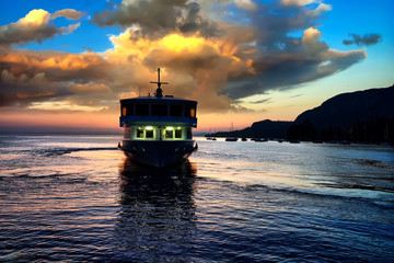 Passenger ship at a wonderful sunset on Lake Garda by the promenade of city Garda