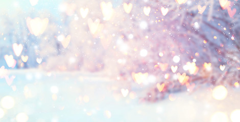 St. Valentine's Day winter blurred background with glowing hearts. Xmas trees with snow, holiday...