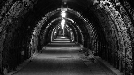 An old, illuminated, hollow underground tunnel in a closed coal mine.