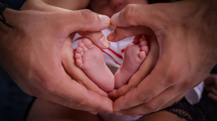 Baby feet between heart-shaped hands