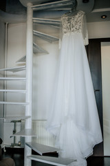 Fototapeta na wymiar Bride's dress on hanger on the stairs in the bride room. Wedding day