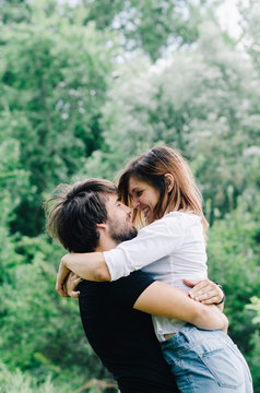 Happy couple kissing and hugging in nature. Young man and woman in loving relationship having fun in park.