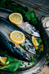 Fresh mackerel fish with lemon and spices served on silver plate from above. Homemade seafood dish recipe cooking.