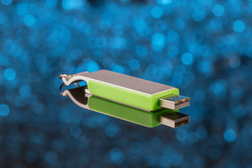 Metal USB flash drive on blue background out of focus