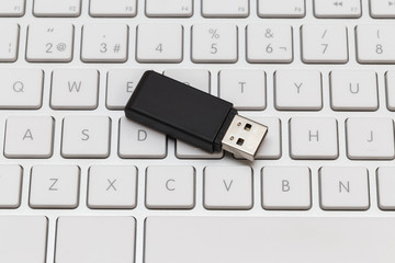 Black USB flash drive on white computer keyboard