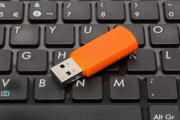Orange USB flash drive on a black computer keyboard
