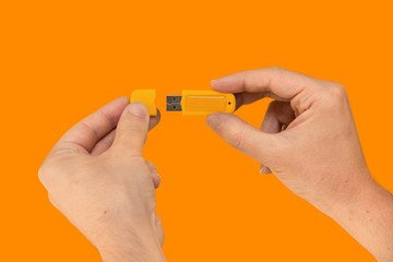 Yellow USB flash memory on hand with isolated orange background