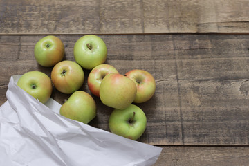 apples in a paper bag on a wooden table