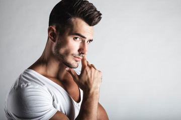 Male beauty concept. Portrait of handsome young man with stylish haircut posing over gray background. Perfect hair & skin. Tough guy. Vogue style. Close up. Studio shot