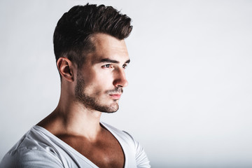 Male beauty concept. Portrait of handsome young man with stylish haircut posing over gray background. Perfect hair & skin. Close up. Studio shot