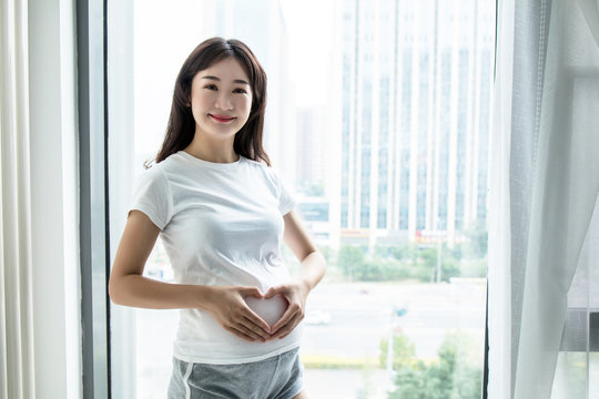 Pregnant Woman Standing Against The Window