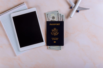 Travel booking flights reservation on the devices tablet touch pad with USA passport and dollar banknotes Planning a trip