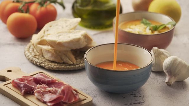 Serving salmorejo in a bowl, with various ingredients around. Salmorejo is a typical Andalusian dish, similar to gazpacho