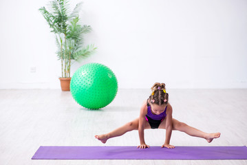 Little girl gymnast doing exercises indoors