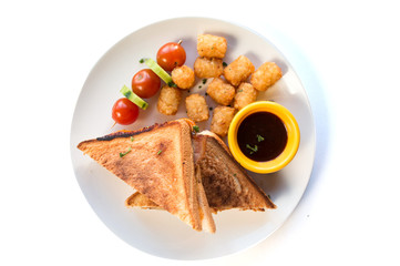 Top view image of two slices of toast bread with hash browns, tomatoes