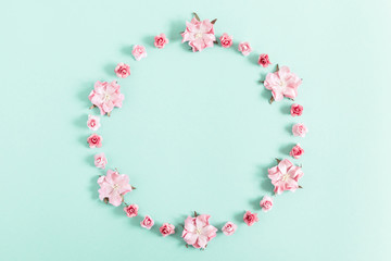 Obraz premium Flowers composition creative. Wreath made of light pink flowers on pastel blue background. Flat lay, top view, copy space