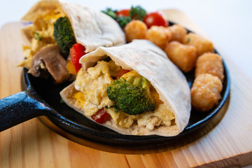 Close up image of Breakfast burrito with vegetables on a wooden plate