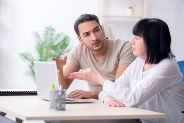 Young male employee explaining to old female colleague how to us