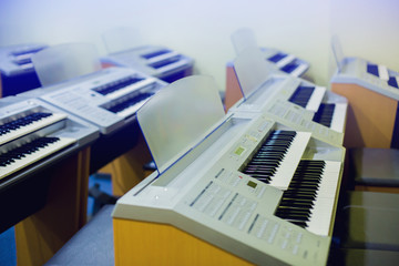 Selective focus to electric piano with many control button in music room. There are musical instrument for learning music.