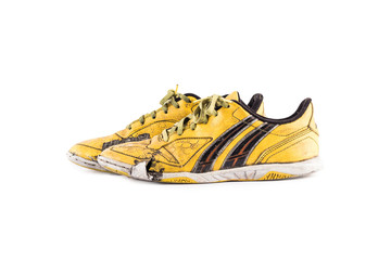 Old  worn out dirty yellow futsal sports shoes  on white background football sportware object...