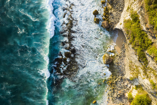 View from above, stunning aerial view of a rocky shore with a beautiful beach bathed by a rough sea during sunset, Nyang Nyang Beach (Pantai Nyang Nyang), South Bali, Indonesia. © Travel Wild