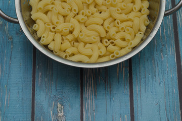 yellow boiled italian pasta in colander on wooden blue background