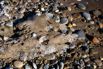 Ice shapes on the beach from rocks and pebbles in the winter