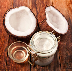 Fresh cracked coconut, coconut meat in a jar and coconut oil in glass cup on wooden background.