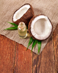 Fototapeta na wymiar Coconut on palm leaves with melted coconut oil in a glass bottle on wooden background. 