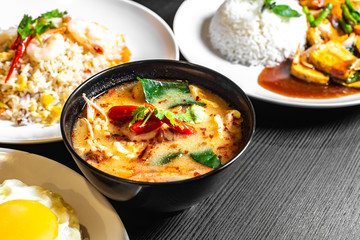 Selective focus of Thai dishes on the table. Tom yum soup, Olive fried rice, and Mixed Vegetables fried rice in the background blurred.