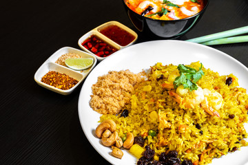 Pineapple Fried Rice and a bowl of Tom Yum Soup in the background. Typical famous Thailand cuisine food on table.
