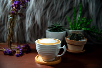 a cup of hot latte with cactus pots and dry flowers.