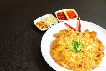 Thai-style Egg Omelette, isolated served in a white plate with chilli padi.