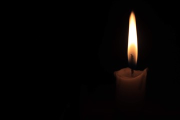 A flame from the candle in darkness.