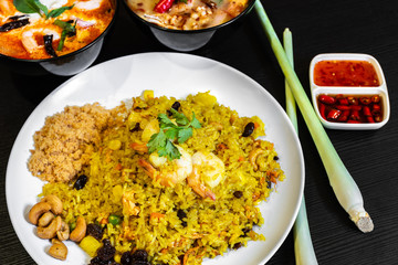 Pineapple Fried Rice and two bowls of Tom Yum Soup in the background. Typical famous Thailand cuisine food on table.