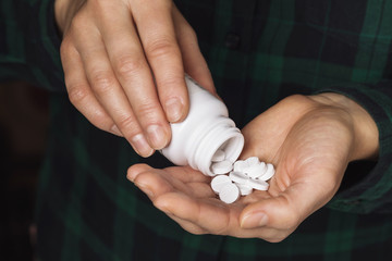 A man pours pills into the palm of his hand, close-up. Medication concept