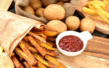 Homemade Crispy Seasoned French Fries..French fries  with spicy seasoning in brown paper bag on wooden broad.