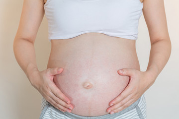 Pregnant smiling Woman caressing her belly. Mom Expecting Baby. Concept of pregnant women healthy and health care.