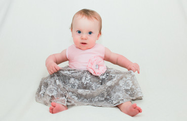 Fototapeta premium Close up Portrait of Cute Little 8 Month Old Baby Girl with Big Blue Eyes, in Pink and Silver Cute Dress, Happy and Healthy Baby