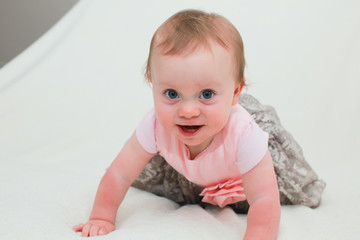 Fototapeta premium Close up Portrait of Cute Little 8 Month Old Baby Girl with Big Blue Eyes, in Pink and Silver Cute Dress, Happy and Healthy Baby