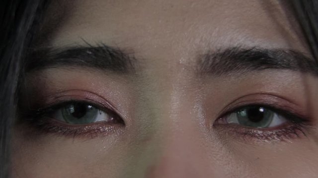 Macro Close Up On Both Eyes Opening Of Young Woman Long Hair And Stare Straight Forward And Look Around On Black Background, Wearing Soft Green Contact Lens