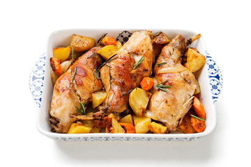 Stewed in white wine with spices rabbit legs with baked vegetables and rosemary. isolated on white background