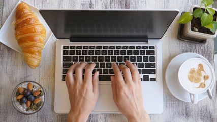 Overhead Of Modern Young Woman Working On Laptop With Coffee