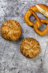 Multicereal seed buns and pretzel on a concrete background